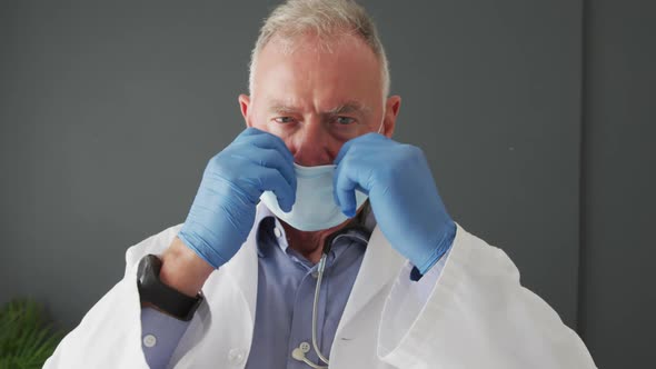 Portrait of caucasian senior male doctor wearing face mask