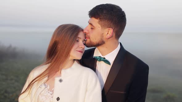 Newlyweds. Caucasian Groom with Bride on the Morning Field. Fog. Wedding Couple