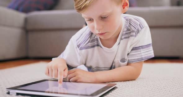 Little Boy at Expressive Face Using a Digital Tablet on the Floor Boy Playing with Digital Tablet