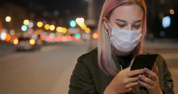 Blonde Woman in Protective Mask Surfs Internet in Telephone