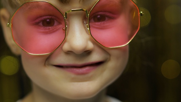Close Up Face of Child. Smiling, Looking at Camera. Girl in Pink Sunglasses Posing