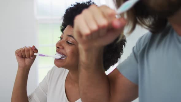 Mixed race couple brushing together in the bathroom