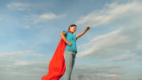 Girl Dreams of Becoming a Superhero. Young Girl Standing in a Red Cloak Expression of Dreams