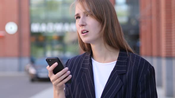 Businesswoman Reacting to Loss while Using Smartphone Outside Office