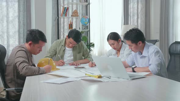 Group Of Asian Engineers Drawing Building Construction At The Office