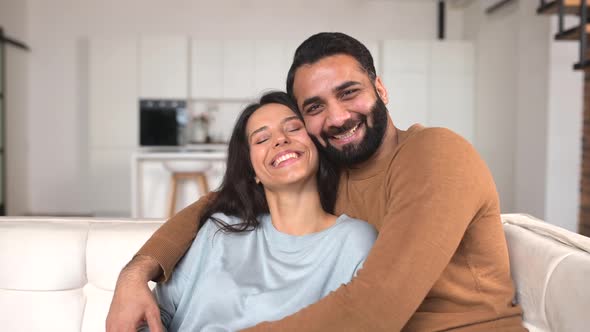 Closeup of Happy Interracial Couple Posing While Sitting at the Sofa with Kitchen Background