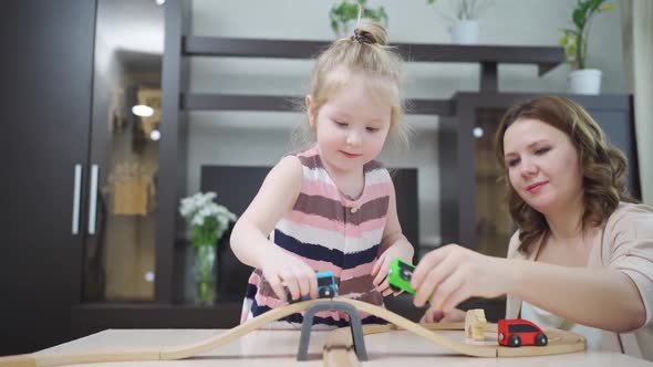 Mom and Daughter Play with Wooden Toy Railway