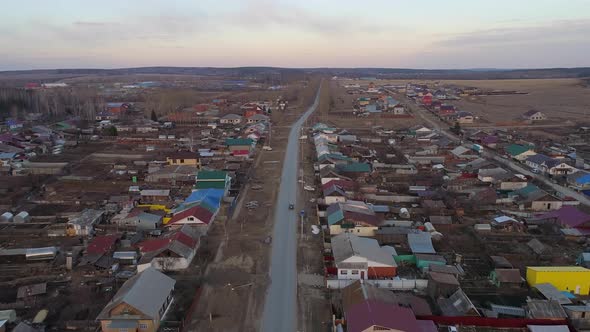 Aerial view of Spring evening in the village. Car are driving along the road