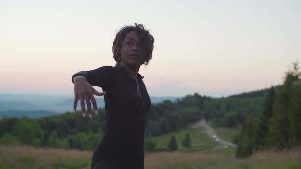 Active Sporty Fit Black Woman Stretching in Yoga Warrior Position in Mountains at Sunrise