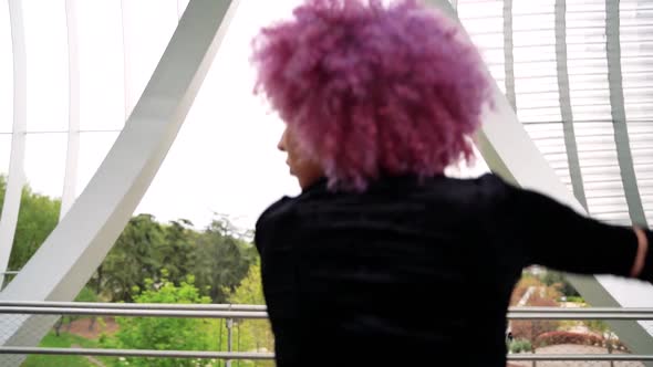 Stylish woman with pink hair dancing outdoors