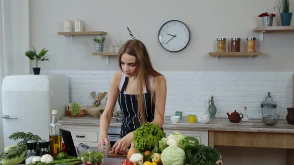 Vegan Girl Cooking Salad with Raw Vegetables While Looking on Digital Tablet for Online Recipe