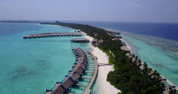 Wide flying travel shot of a sunshine white sandy paradise beach and turquoise sea background in col