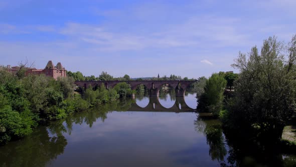 The Old Bridge of Montauban France crossing the Tarn River with car traffic, Aerial approach shot