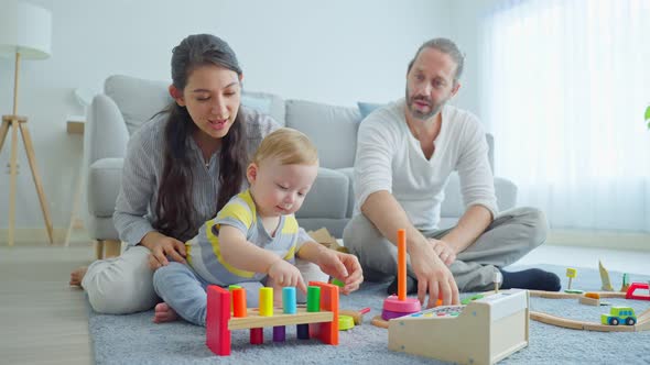 Caucasian happy family, loving parent play with baby toddler in living room enjoy activity at home.