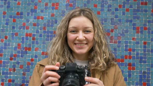 Woman Poses for Camera and Takes Photo Against Tiles on Wall
