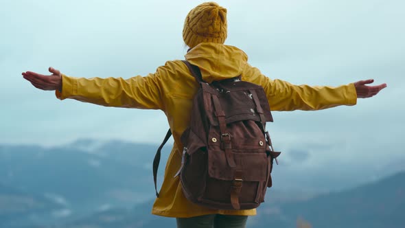 Rear View Woman in Mountains Wearing Yellow Warm Clothes with Backpack