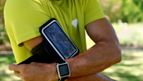 Man adjusting his armband in park 4k