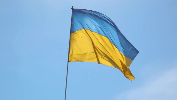 The Ukrainian Flag Flutters Against the Blue Sky