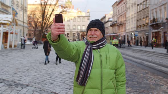 Elderly Tourist Grandfather Traveling Taking Selfie Making Online Video Call on Winter City Center