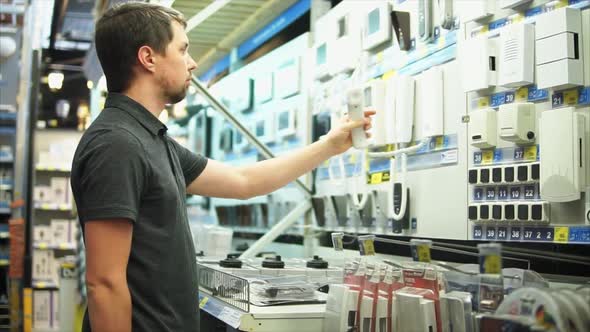 Man in the Electronics Shop is Choosing Intercom Security System and Alerts