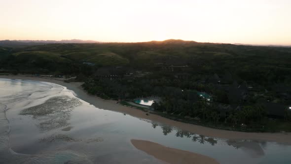 Low tide at Natadola Bay on mainland Fiji during sunrise over hills, aerial