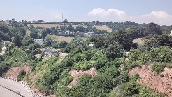 Aerial shot of the Jurassic Coast with trees revealing houses in the background.