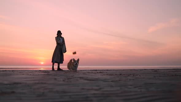 Dog and Woman in Hat Playing on Te Beach Background Sunset Spbi