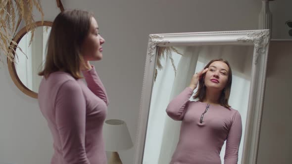 Portrait of Happy Beautiful Adult Woman Admiring Her Appearance in Mirror at Home