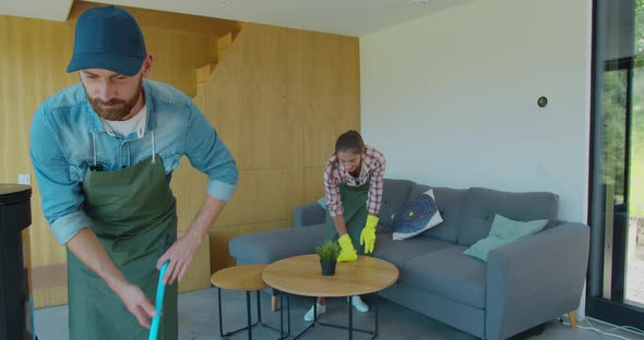 Professional Cleaners in Uniform Washing Floor and Wiping Dust From the Furniture in the Living Room