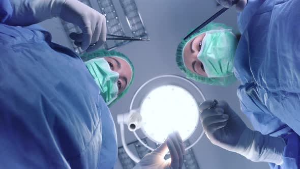 From Below Female Surgeons in Medical Uniform Using Professional Tools While Standing Under Bright