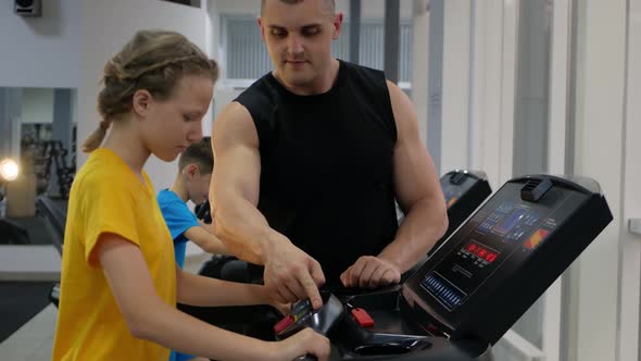 Coach Helps Children Perform Physical Exercises in Gym