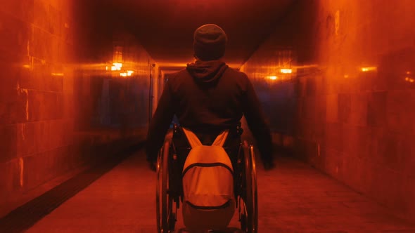 Disabled Man in Wheelchair Riding in the Empty Underpass at Evening