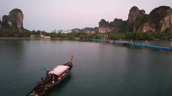 Thai longtail boat arriving at the docks in Railay Beach of Krabi Thailand during sunrise with large