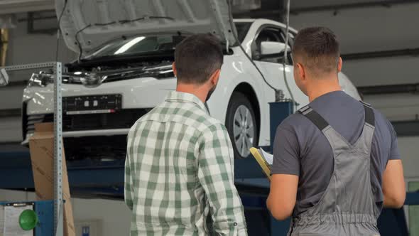 Rear View Shot of a Mechanic and Customer Shaking Hands at the Garage