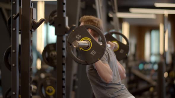 Young Fitness Man Doing Barbell Squats at Gym. Sportsman Training in Sport Club