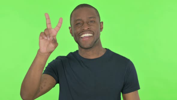 Victory Sign By Young African Man on Green Background