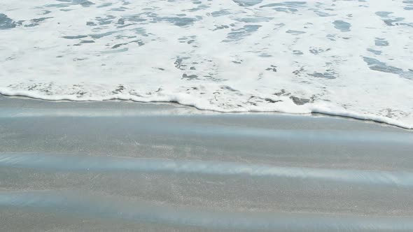 Closeup of a wave as it rushes onto the beach in slow motion.