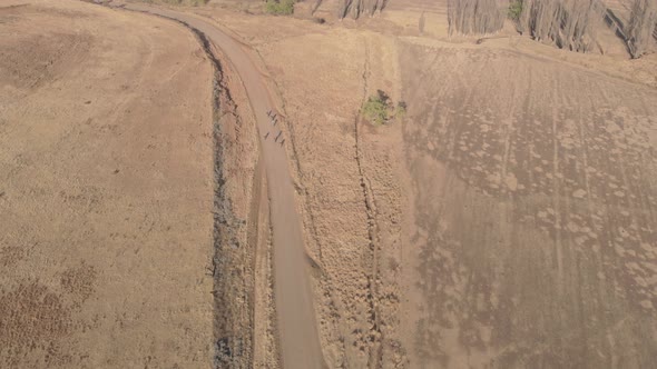 aerial shot following a group of mountain bikers racing on a gravel road