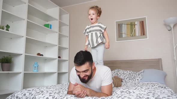 Happy Father Enjoys Spending Time with His Daughter, Little Girl Is on Back of Father