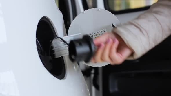 Footage of Charging of Eco Friendly Electric Car. Close Up Womans Hand Unplugging Charger From