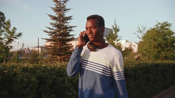 Portrait Joyful Happy Young Black Guy in Casual Clothes Talking on Smartphone Walk Street