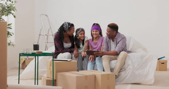 A Happy Family Sits on Couch in Apartment During Renovation Married Couple and Their Two Daughters