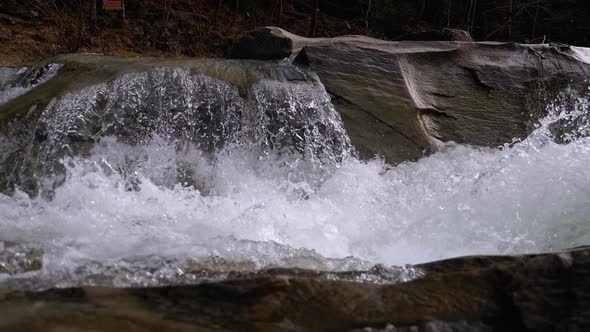 Mountain Creek and Stone Rapids with Snow. Rapid Flow of Water. Winter Waterfall. Slow Motion