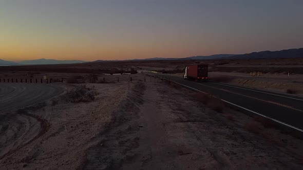 Trucking with Cargo on Freeway in Salton Sea Desert with Glowing Sky at Dusk , California - static