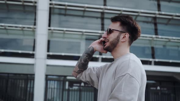 Handsome Young Stylish and Modern Man Talking on the Phone with Smile While Walking Around the City