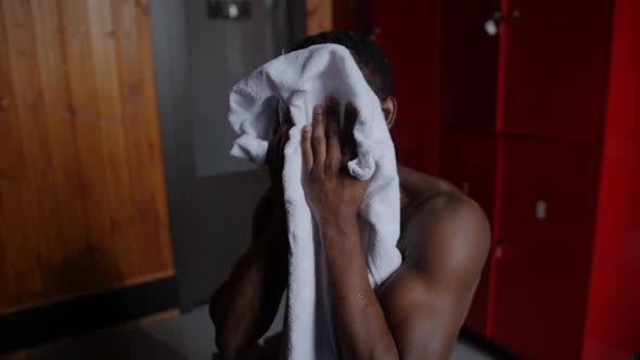 Africanamerican Athletic Young Man Wipes Off His Head with a Towel in Locker Room