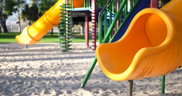 Close up of a yellow slide in an empty kids park playground with bokeh and copy space in the backgro