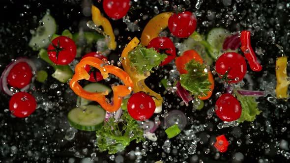 Super Slow Motion Shot of Flying Cuts of Colorful Vegetables and Water Drops on Black at 1000Fps