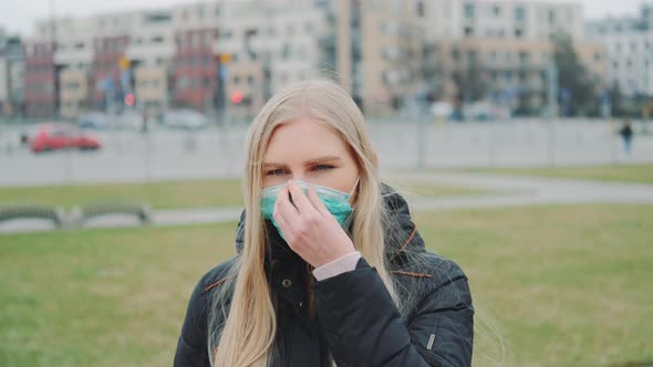 Young Woman Putting a Medical Mask on Her Face on the Street