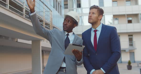 Diverse Business People Wearing Hardhat and Holding Tablet Inspecting Construction Site Outside